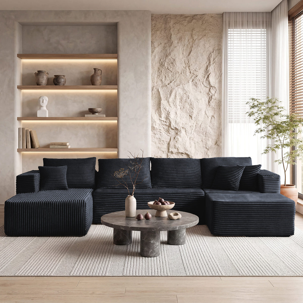 [Black] corduroy U-shaped sectional sofa — full front view in modern minimalist living room with stone round coffee table and built-in illuminated shelving, showing 4-seat plus dual chaise layout