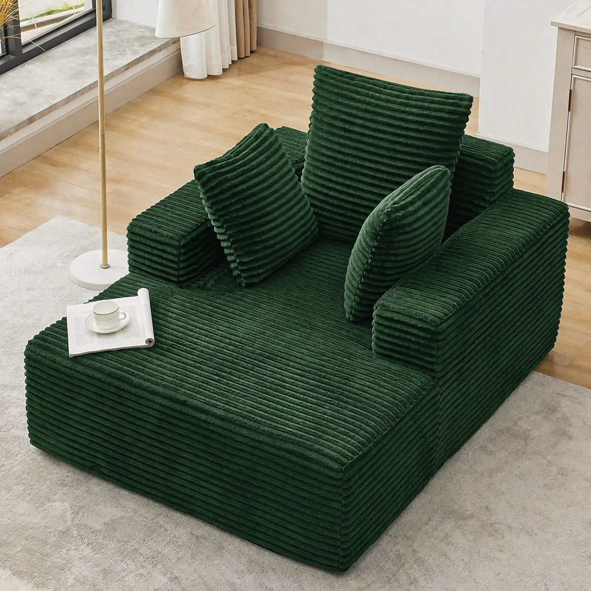 [Green] oversized corduroy chaise lounge chair — angled full view showing deep seat, wide armrests, and three throw pillows